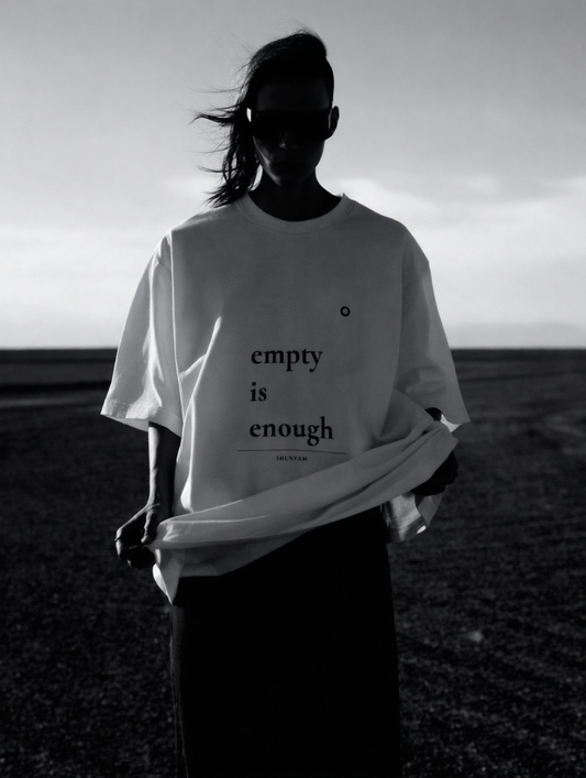 Person wearing a white t-shirt with 'empty is enough' text in a black and white landscape.