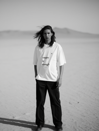 Person wearing a white t-shirt with text in a desert setting