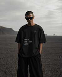 Person wearing a black t-shirt with 'ZERO EXCUSES LEFT' text in a desert landscape